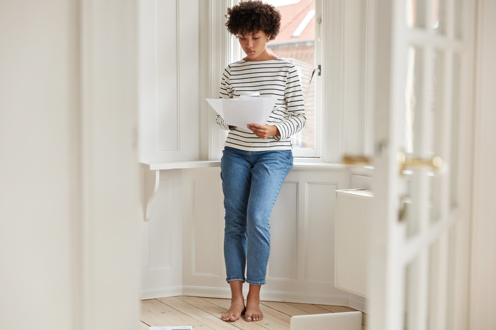 Horizontal shot of pleasant looking busy young woman studies provision for taxation, holds papers, d